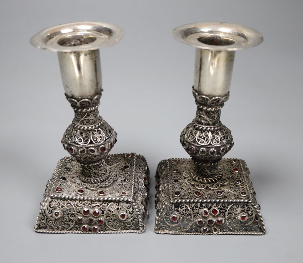 A pair of continental filligree white metal and red stone set dwarf candlesticks (possibly Malta), 11.4cm, weighted.